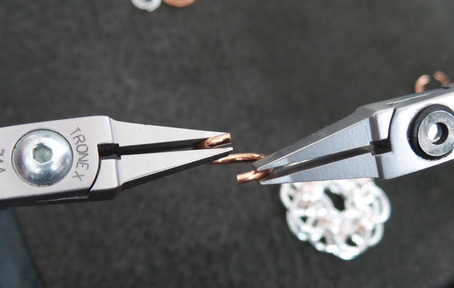 Two pairs of pliers closing a copper jump ring