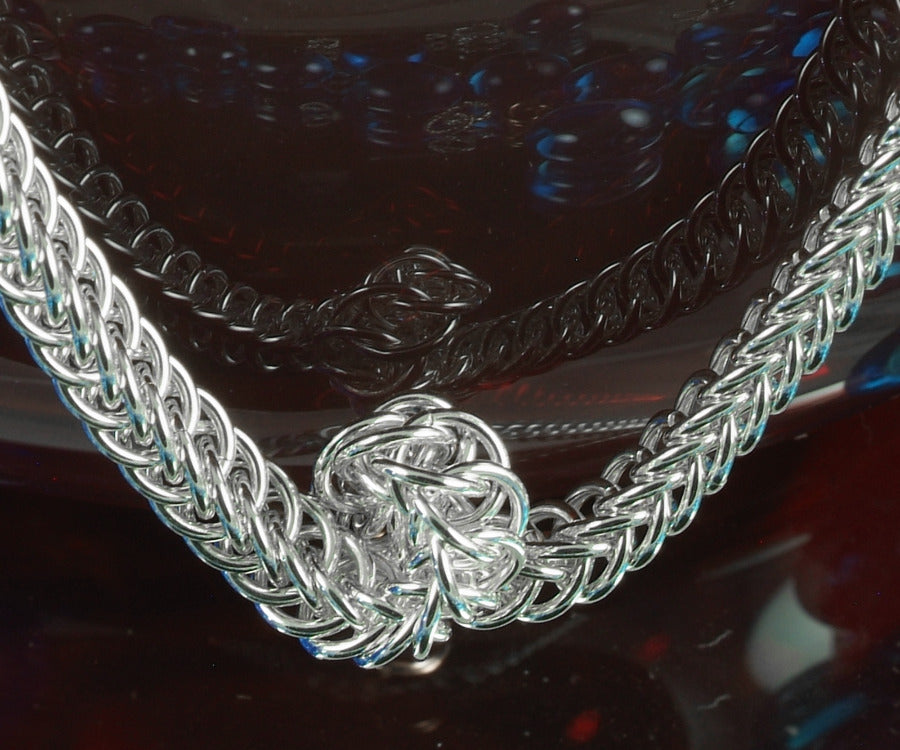 Close-up of the Serpentine necklace twist in sterling silver Half Persian 4-in-1 chainmaille on red glass
